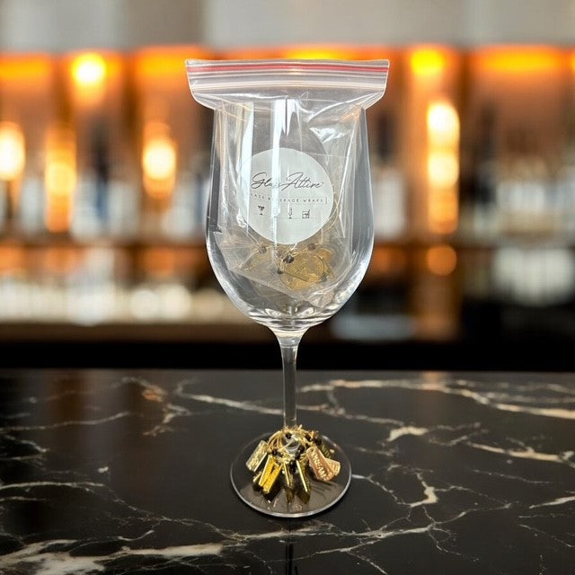 Clear wine glass with decorative base on a marble surface, blurred bar background