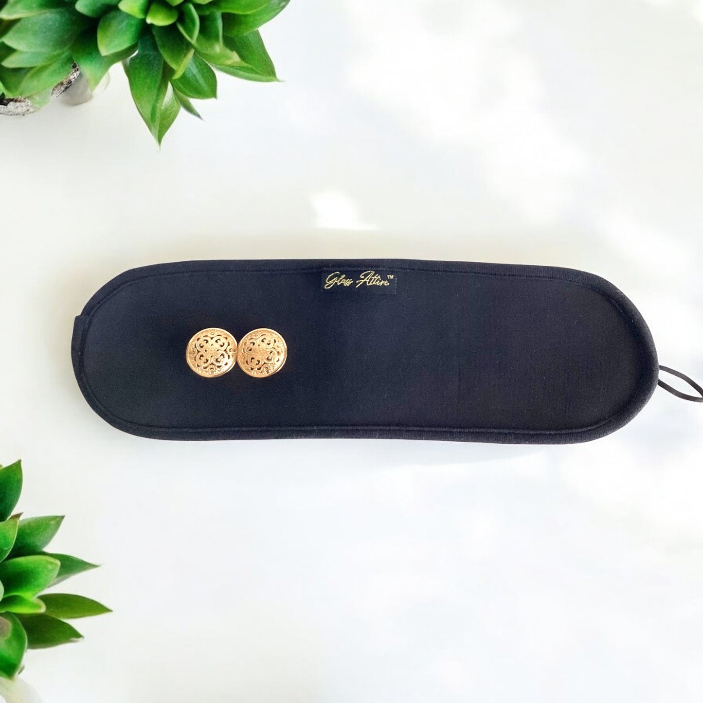 Black highball wrap with gold buttons on a white background with green plants.