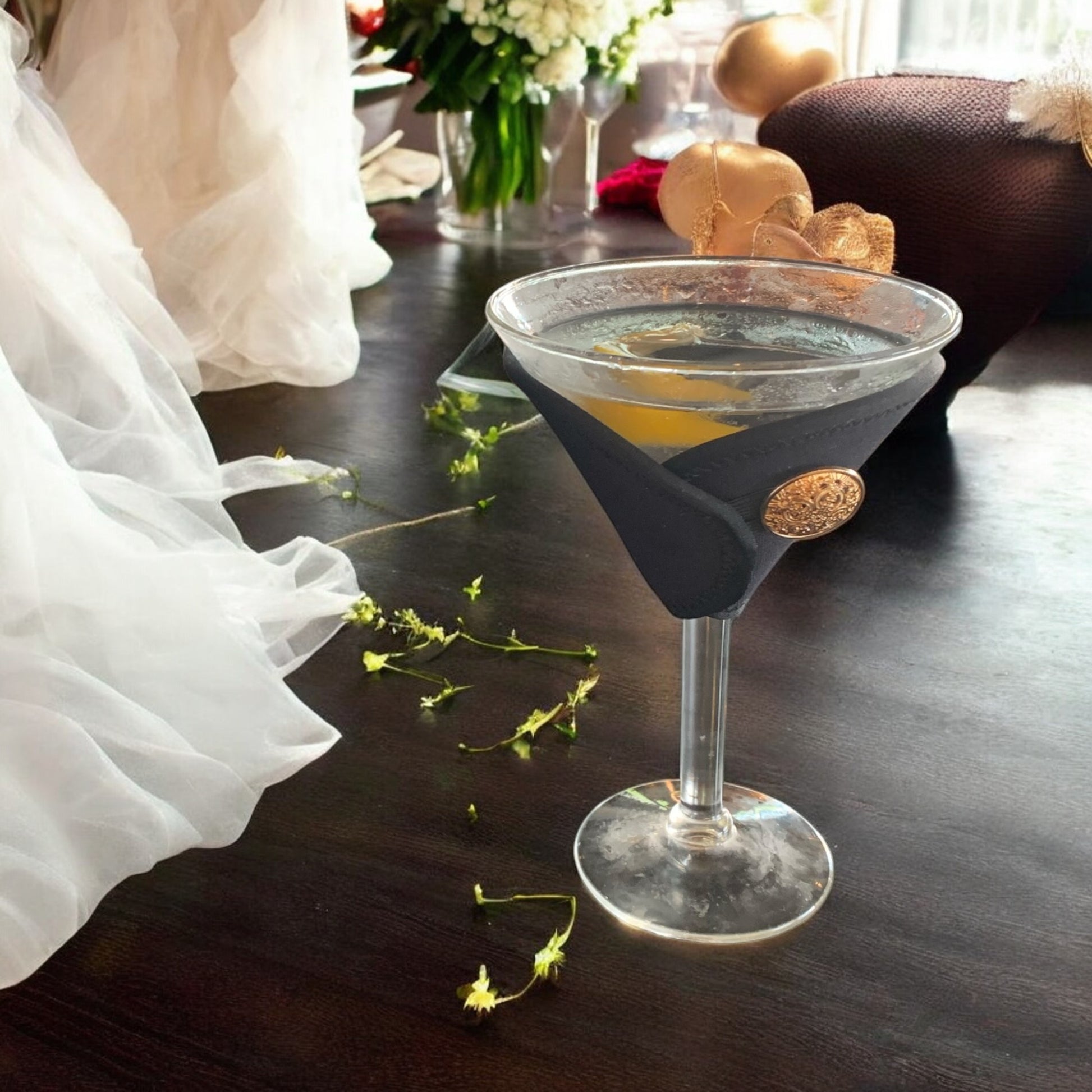 Cocktail glass with a black sleeve on a wooden table with decorative elements.